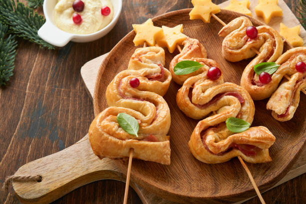 istock Christmas or New Year appetizer. Christmas tree shape puff pastry buns with cheese and ham. Group of Christmas tree shapes on wooden board. Festive idea for Christmas or New Year dinner. Top view. 1457407045