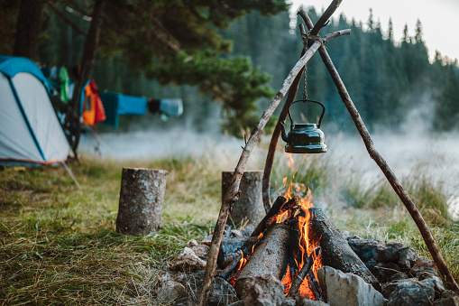 Shot of retro teapot hanging over the campfire in the morning.