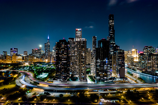 Cars zoom by Chicago's skyline lit up at night