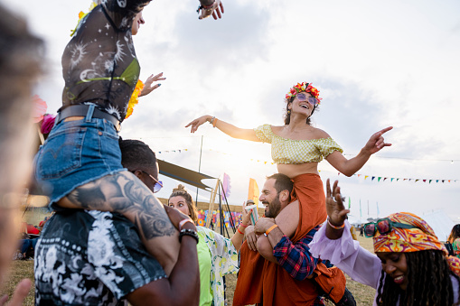 A small group of male and female friends shoulder carrying each other at a festival in Northumberland in the north east of England. They are all embracing each other and having fun.