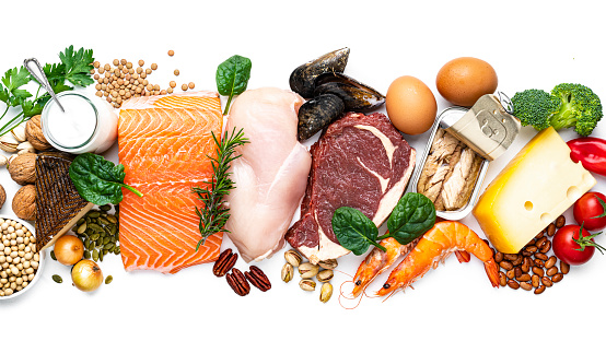 Overhead view of a large group of food with high content of healthy proteins arranged side by side on white background making a banner. The composition includes salmon beef fillet, chicken breast, eggs, yogurt, mussels, chick peas, pistachios, cheese, brown lentild, beans, shrimps, canned tuna, pumpkin seeds, soybeans among others. High resolution 42Mp studio digital capture taken with SONY A7rII and Zeiss Batis 40mm F2.0 CF lens
