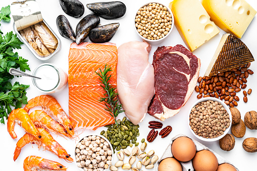 Overhead view of a large group of food with high content of healthy proteins. The composition includes salmon beef fillet, chicken breast, eggs, yogurt, mussels, chick peas, pistachios, cheese, brown lentild, beans, shrimps, canned tuna, pumpkin seeds, soybeans among others. High resolution 42Mp studio digital capture taken with SONY A7rII and Zeiss Batis 40mm F2.0 CF lens