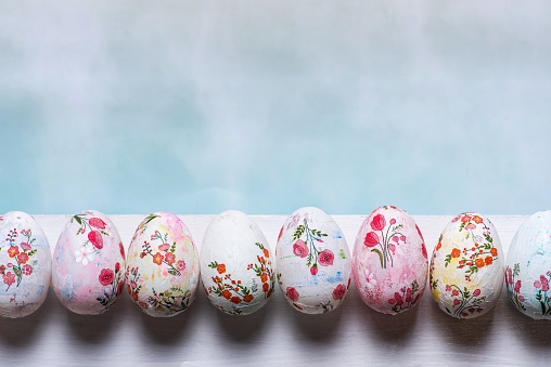 Easter eggs decorated with decoupage technique on a white board on a light blue background.