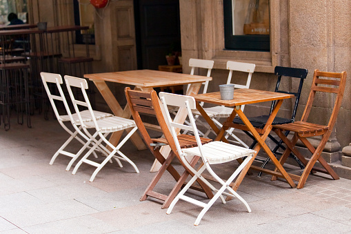Sidewalk cafe, row of wooden chairs and tables narrow city street, old town Pontevedra, Rías Baixas, Galicia, Spain.