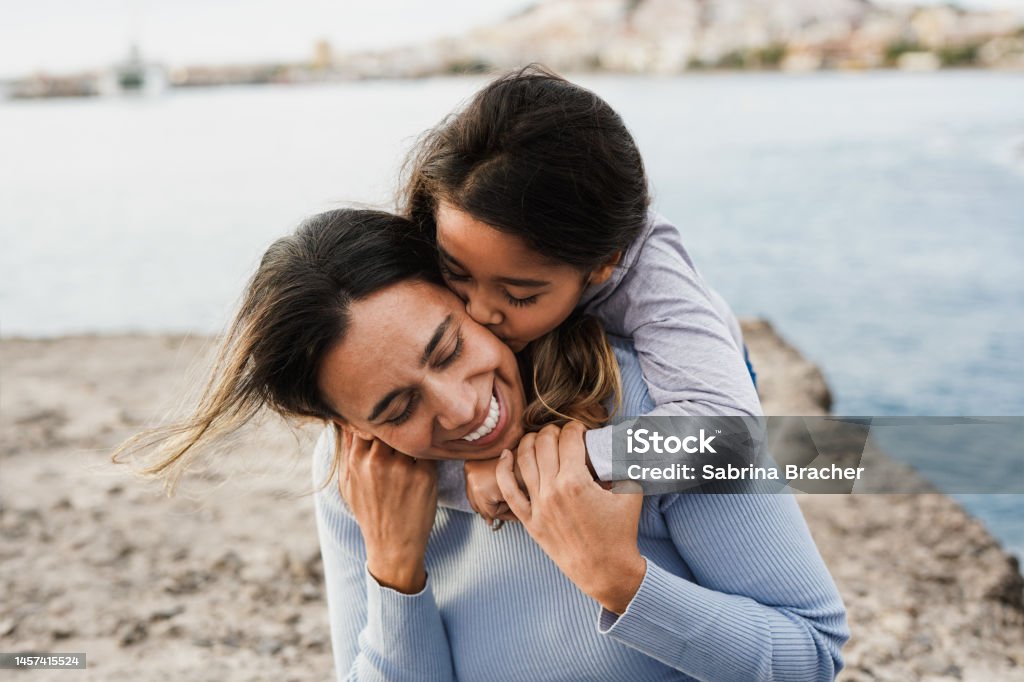Happy latin mother and female child having tender moment together on the beach - Concept of mothers day and family love Life Events Stock Photo