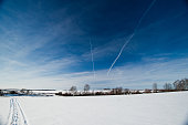 Cold winter landscape with deep blue sky, snow fields and tracks in the snow.