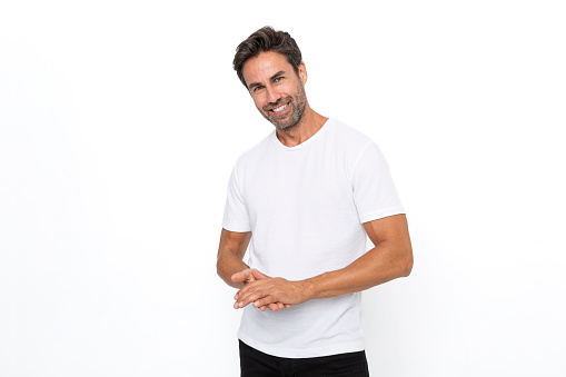 Smiling middle-aged, handsome hispanic man standing wearing blank white t-shirt with copy space isolated on background.