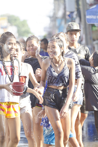 Portrait of wet thai teenagers at Songkran festival. people are walking totally wet and happy along street Chokchai 4 in Bangkok Ladprao. They are wearing shorts and some have buckets with white wet powder