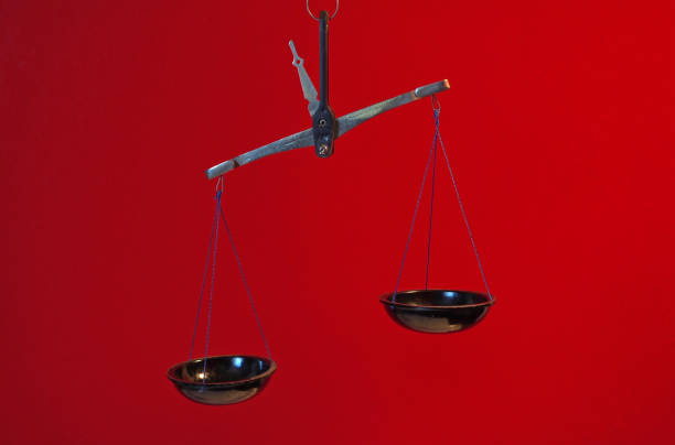 Vintage scales with a metal handle and black bowlsagainst a red background. Symbol of justice.