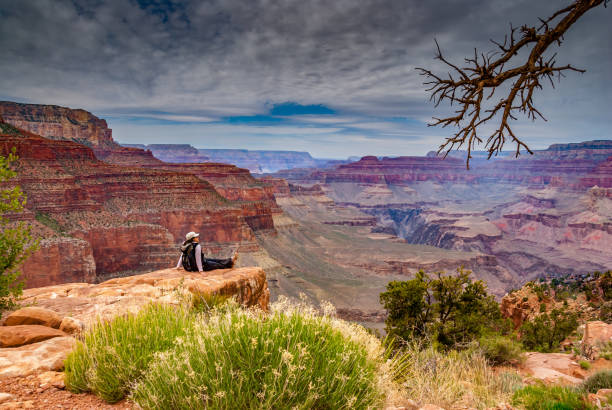 deportivas mujer joven sentada en el borde del cañón - colorado plateau fotografías e imágenes de stock