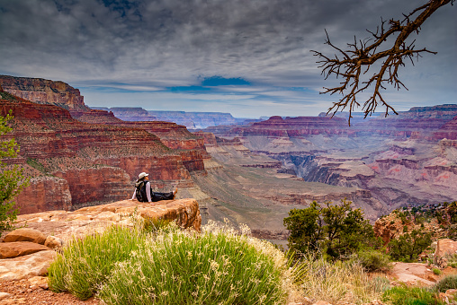 A young woman hiker is sitting on the canyon rim near O'Neil Butte in Grand Canyon National Park, Arizona, USA.