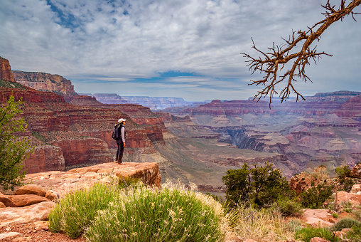 A young woman hiker is standing on the canyon rim near O'Neil Butte in Grand Canyon National Park, Arizona, USA.