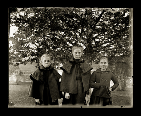 Beautiful Black and White portrait of a three young woman wearing Victorian-era Winter clothing. The image was digitally restored from a glass plate taken circa 1890.
