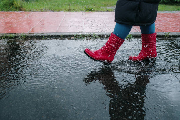 istock Woman with boots splashing on a puddle 1457425779