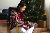 Young adult asian woman opening gift boxes of Christmas advent calendar