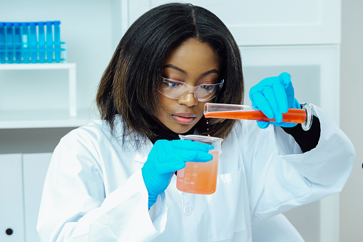 female scientist mixing liquids at laboratory.