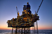 Offshore oil and gas platform in the sea at sunset. 
Jack up rig crude oil production in ocean.