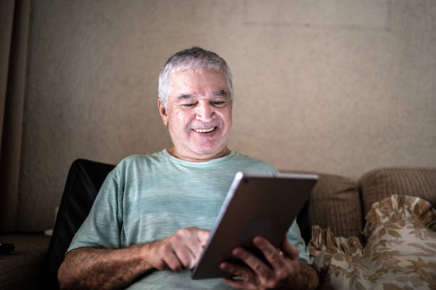 istock Senior man using digital tablet in sofa at home 1457437004