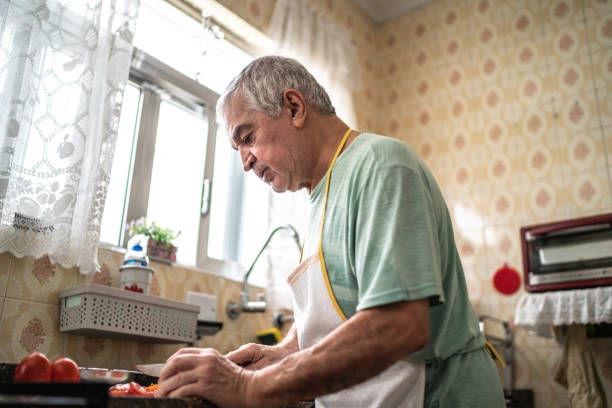 istock Senior man cutting vegetables in kitchen at home 1457441981