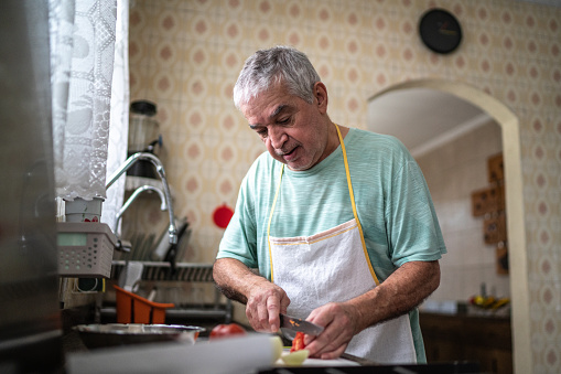 Senior man cutting vegetables on the chopping board in kitchen at home