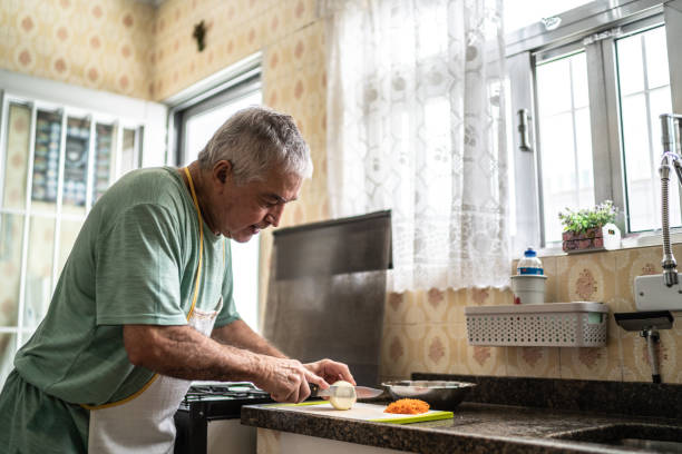 istock Senior man cutting onion in kitchen at home 1457442048