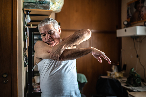 Senior man stretching arms at home