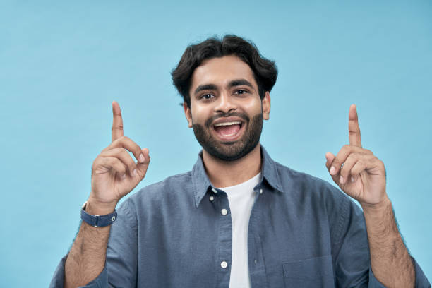 istock Excited arab man pointing up advertising ecommerce offer isolated on blue. 1457443476
