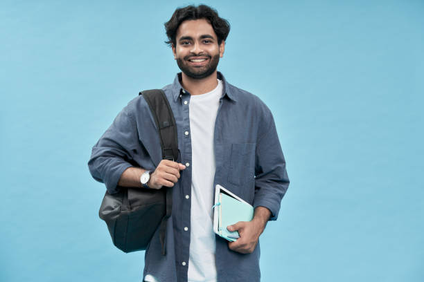 istock Smiling arab young man student standing isolated on blue background. 1457443532
