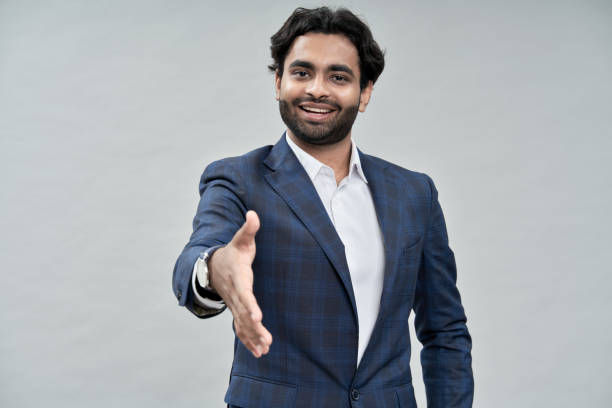 sorridente uomo d'affari arabo che allunga la mano per stretta di mano isolata sul beige. - middle eastern ethnicity business greeting handshake foto e immagini stock