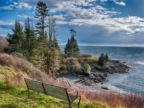 One bench looks over a rocky point and a beach on San Juan Island during a sunbreak in winter.