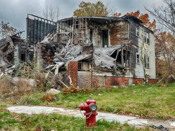 Destroyed Home With Fire Hydrant A red fire hydrant stands in front of a burned and semi-demolished house in a neighborhood of Detroit, Michigan. highland park michigan stock pictures, royalty-free photos & images