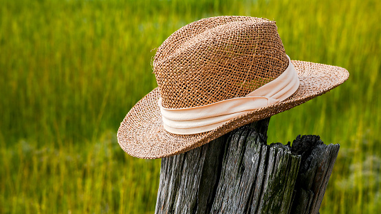 Straw hat outdoor on old wood isolated on beach grass and copy space