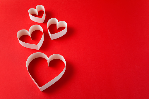 Heart shaped papers on red background with copy space