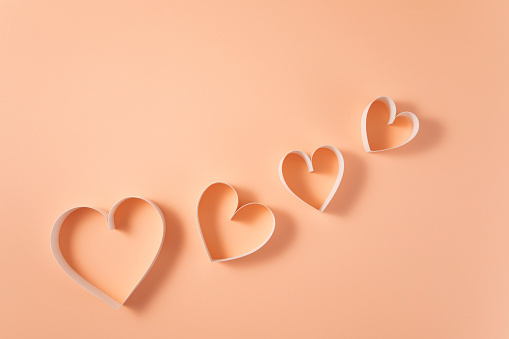 Heart shaped papers on pink background with copy space