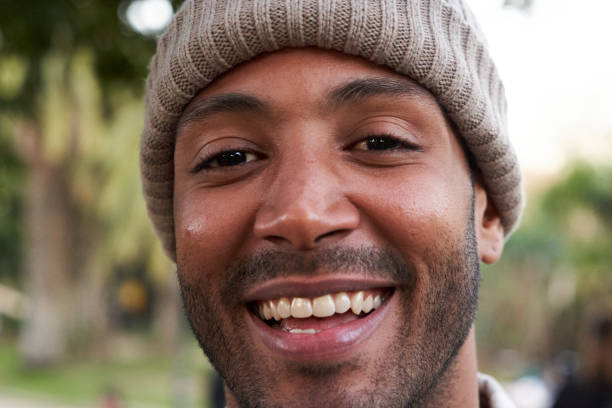 Portrait of mixed race man smiling and looking at camera. Friendly happy African American male person outdoors. Close up.