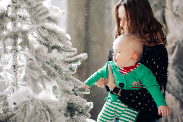 istock Mother plays with her baby son near Christmas tree. 1457460780