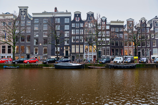 Amsterdam, Holland- Dec 13, 2017. Jewel of North Europe: Amsterdam, city of hundreds of Canals and countless bicycles. This world known city is famous for it's history, architecture water ways and liberal society. Canals of Amsterdam are filled with house boats, barges and all kinds of floating transportation. Over all those canals, there are numerous bridges filled with pedestrians, and unknown number of bicycles. Nice early summer day with canal architecture shown in it's full beauty.