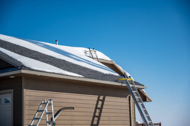 Multiple ladders setup on a residential roof covered in snow as gutters are being installed.