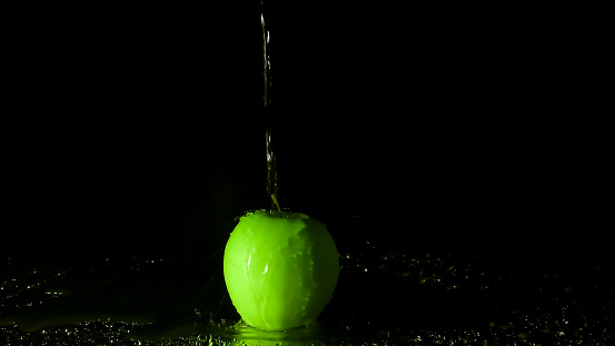 Green apple with water splash on black background