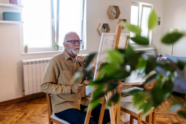 istock Senior man painting a picture on canvas. 1457468800