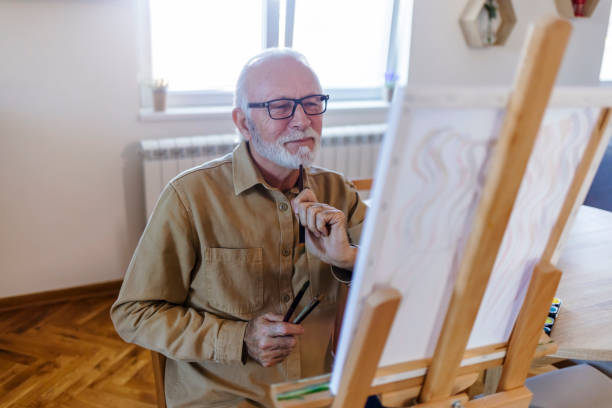 istock Senior man painting a picture on canvas. 1457468922