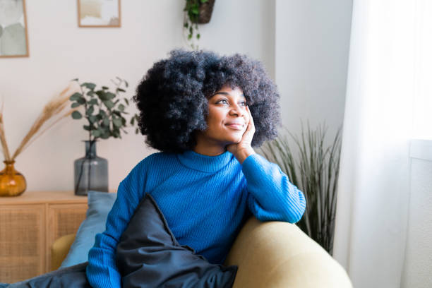 istock Cheerful black woman sitting on couch 1457471847