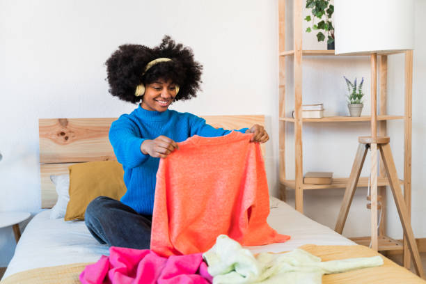 istock Cheerful black girl in bedroom browsing her clothes 1457472532