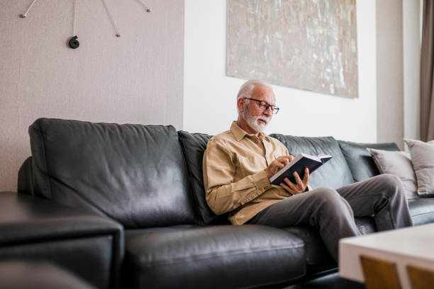 istock Senior Man reading book at home 1457474338