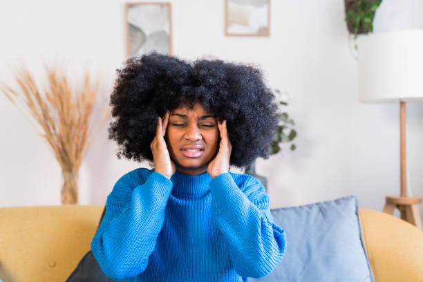 istock Cheerful black woman sitting on sofa and headache 1457477160