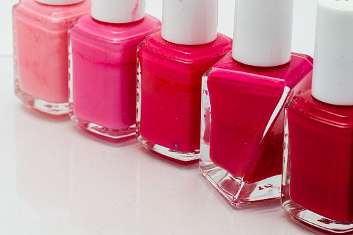 Row of nail polish bottles in different pink colors.