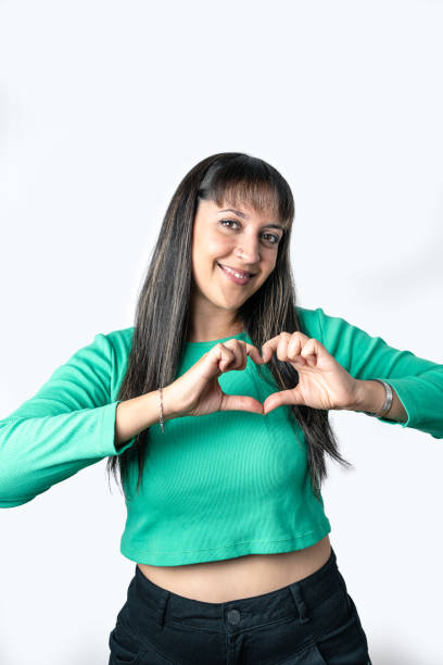 istock Young Latin woman making a heart shape with her hands, isolated on white background 1457483789