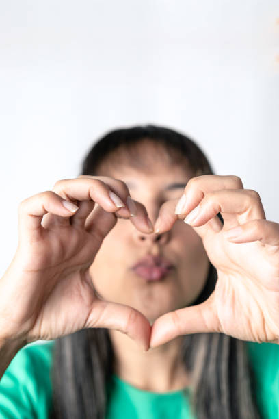 istock Young woman making a heart shape with her fingers on white background 1457483828
