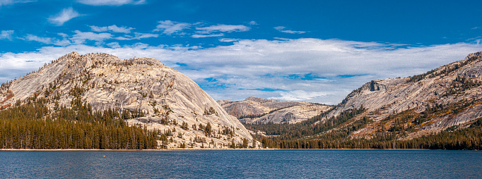A beautiful view of the crisp waters of Tenaya Lake in Yosemite National Park beneath rocky mountainsides.