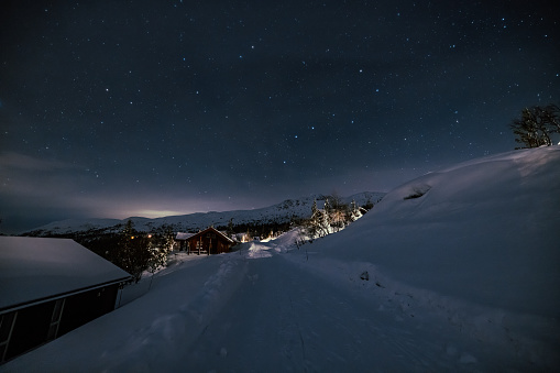 Epic mountain landscape with stars of the milky way and Holiday Christmas Cabin House